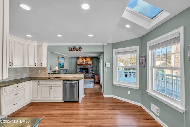 kitchen with sink, white cabinetry, dishwasher, kitchen peninsula, and light hardwood / wood-style floors