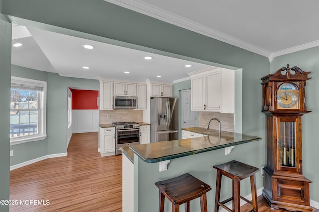 kitchen featuring white cabinetry, appliances with stainless steel finishes, kitchen peninsula, and light wood-type flooring