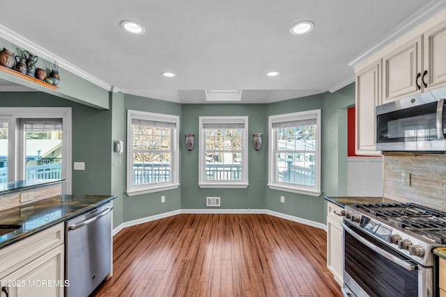 kitchen with decorative backsplash, wood-type flooring, plenty of natural light, and appliances with stainless steel finishes