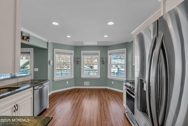 kitchen featuring appliances with stainless steel finishes, sink, light wood-type flooring, and white cabinets