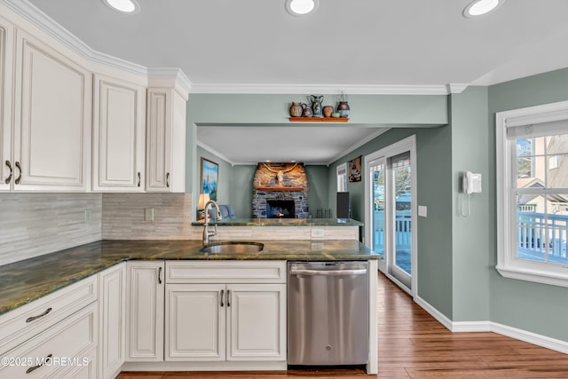 kitchen featuring white cabinetry, sink, stainless steel dishwasher, kitchen peninsula, and plenty of natural light