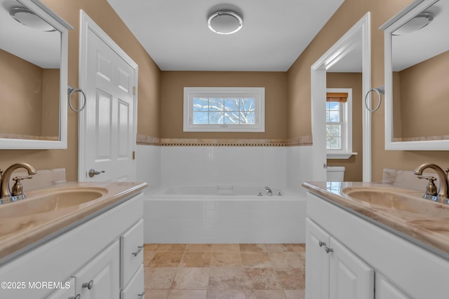 bathroom featuring plenty of natural light, tiled bath, and vanity