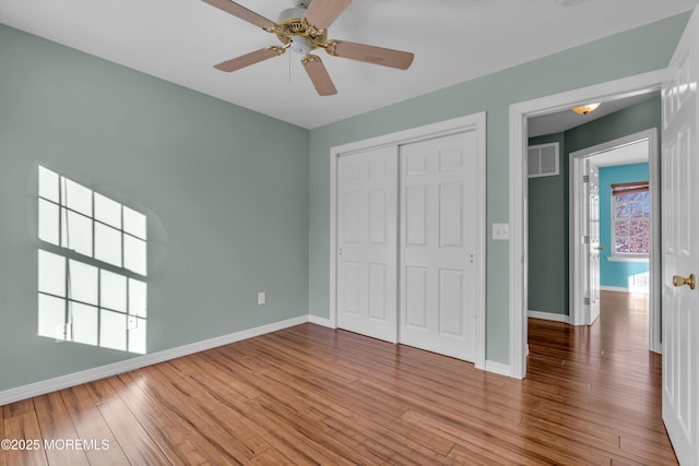 unfurnished bedroom with hardwood / wood-style flooring, ceiling fan, and a closet