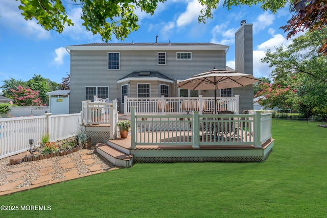 rear view of property with a wooden deck and a lawn