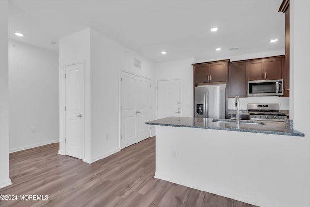 kitchen featuring stainless steel appliances, sink, dark brown cabinets, and dark stone countertops