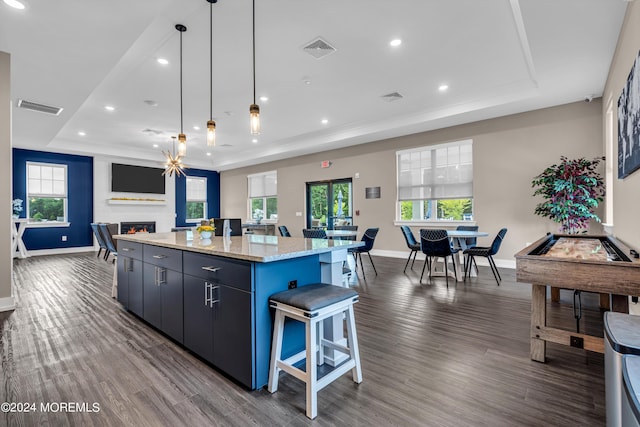 kitchen with a raised ceiling, a large island, a large fireplace, and decorative light fixtures