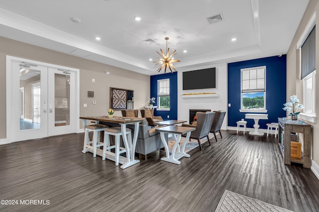 dining space featuring a fireplace, a chandelier, a tray ceiling, dark wood-type flooring, and french doors