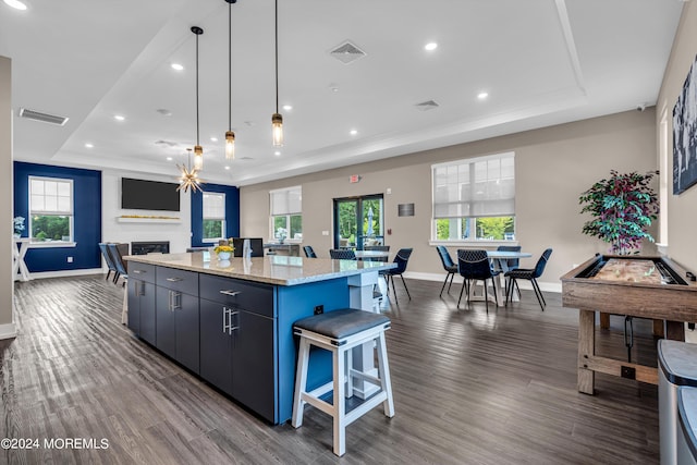 kitchen with hanging light fixtures, a large island, dark hardwood / wood-style flooring, and a tray ceiling