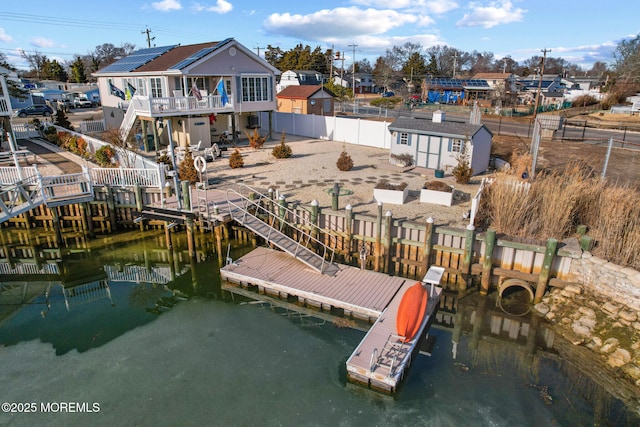 exterior space featuring a deck with water view, a storage shed, and solar panels