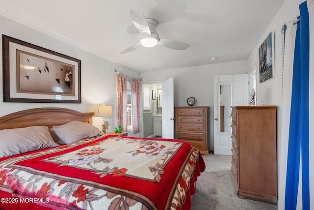 bedroom with ceiling fan, light colored carpet, and ensuite bath