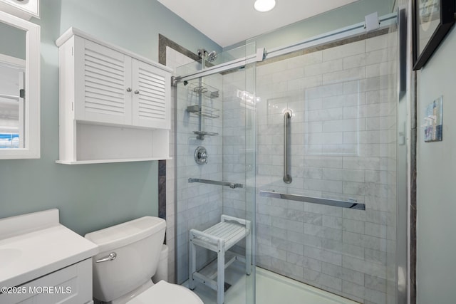 bathroom with vanity, toilet, and a shower with door