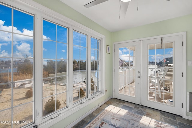 unfurnished sunroom featuring a wealth of natural light, ceiling fan, and french doors