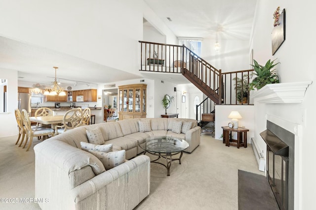 living room featuring a chandelier, a high ceiling, light carpet, and a baseboard heating unit