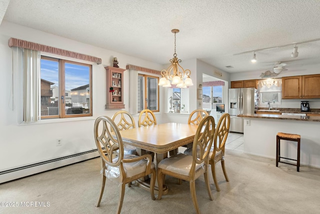 dining space featuring sink, a baseboard heating unit, light carpet, and a textured ceiling