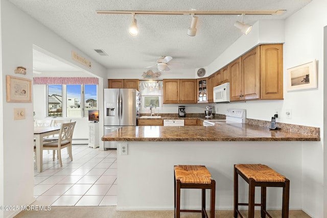 kitchen with white appliances, kitchen peninsula, a breakfast bar area, and a textured ceiling