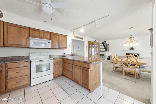 kitchen with pendant lighting, rail lighting, white appliances, light carpet, and a textured ceiling