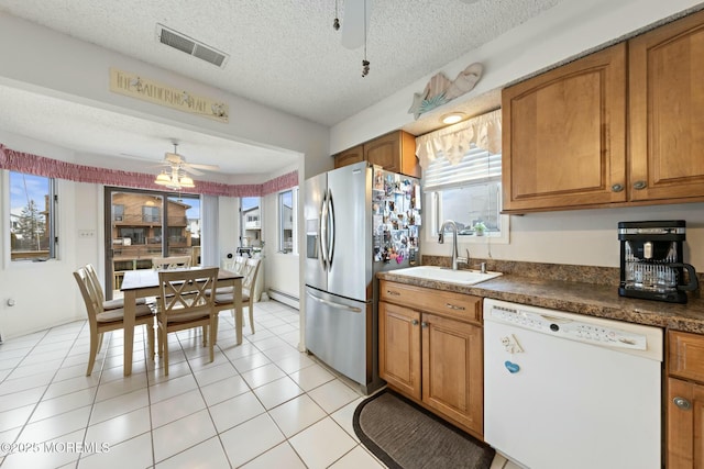 kitchen with stainless steel fridge, dishwasher, sink, and a textured ceiling