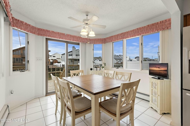 tiled dining room with baseboard heating, a healthy amount of sunlight, and a textured ceiling