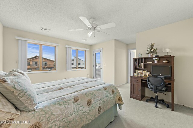 bedroom featuring ceiling fan, light colored carpet, and a textured ceiling