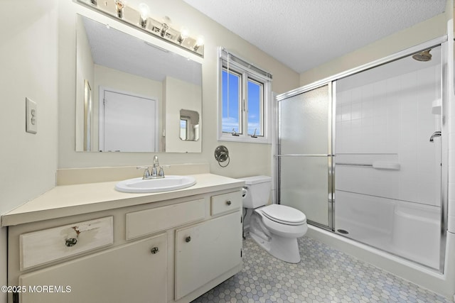 bathroom with a shower with door, vanity, a textured ceiling, and toilet