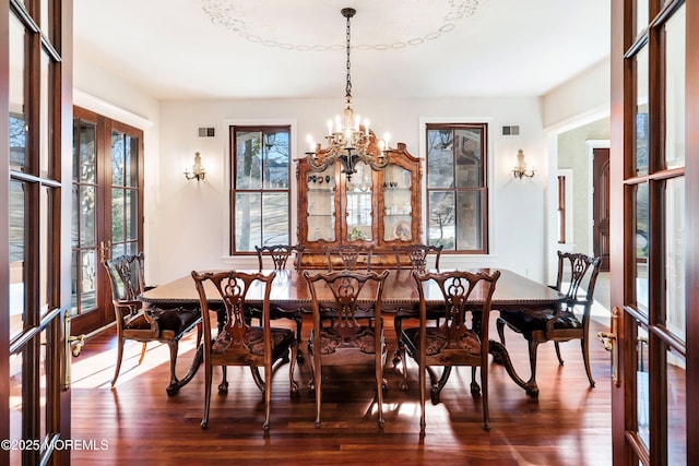 dining space featuring a notable chandelier, dark hardwood / wood-style floors, and french doors