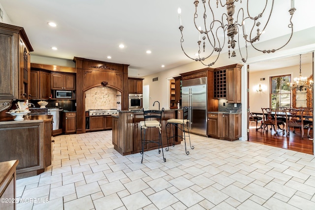 kitchen with a kitchen island, a breakfast bar, hanging light fixtures, stainless steel appliances, and an inviting chandelier