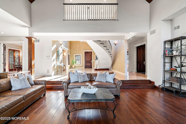 living room with dark hardwood / wood-style floors, a high ceiling, and ornate columns