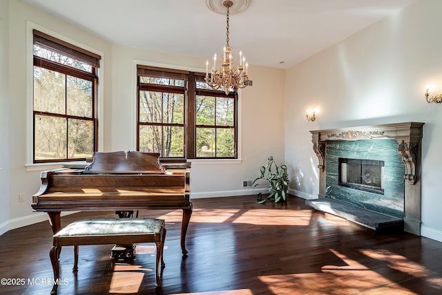 misc room featuring dark wood-type flooring, plenty of natural light, a premium fireplace, and a chandelier