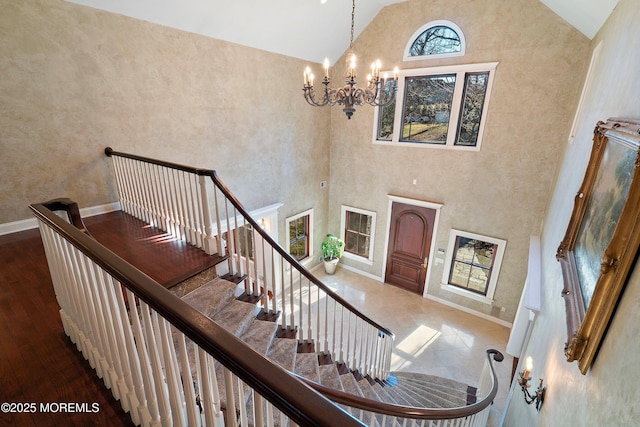 stairway with hardwood / wood-style floors, high vaulted ceiling, and a chandelier