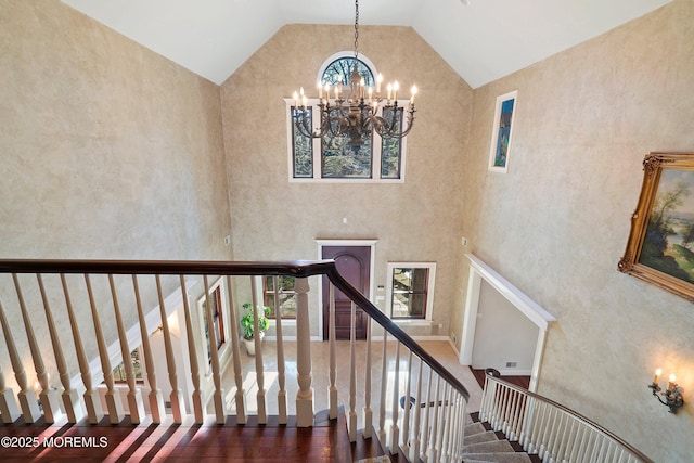 stairway featuring a wealth of natural light, a notable chandelier, and high vaulted ceiling