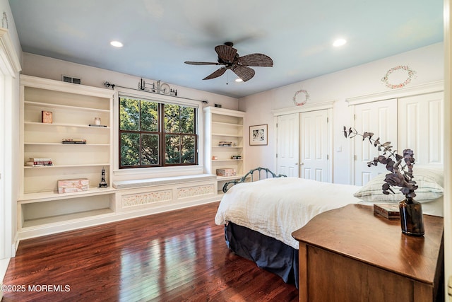 bedroom featuring dark wood-type flooring, two closets, and ceiling fan