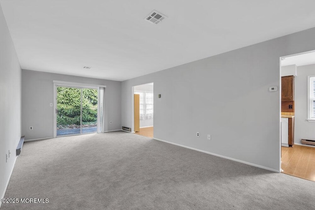 carpeted spare room featuring a baseboard heating unit