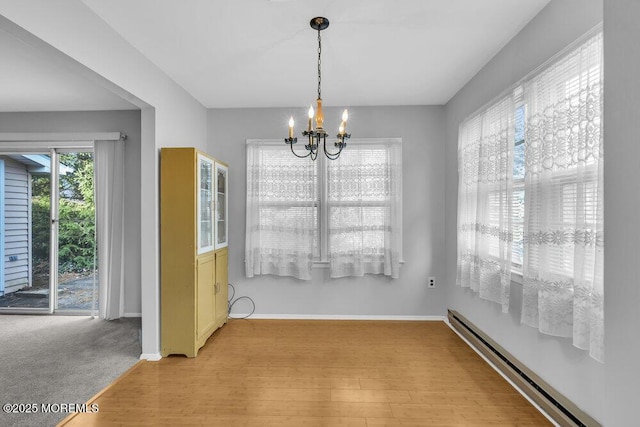 unfurnished dining area with a chandelier, light hardwood / wood-style floors, and a baseboard heating unit