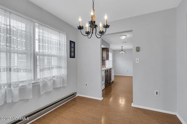 unfurnished dining area featuring baseboard heating, wood-type flooring, and a notable chandelier