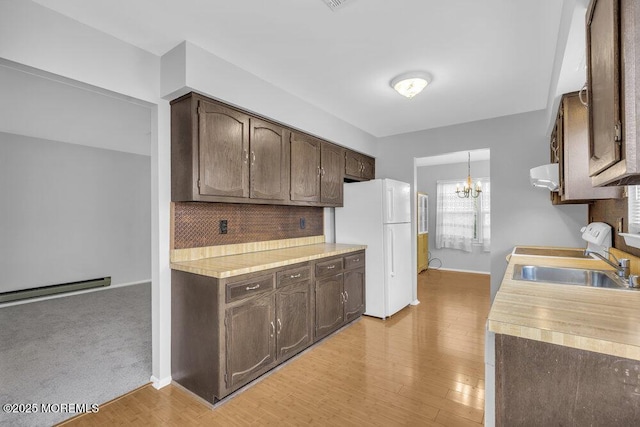 kitchen with decorative backsplash, dark brown cabinets, a baseboard radiator, and white refrigerator