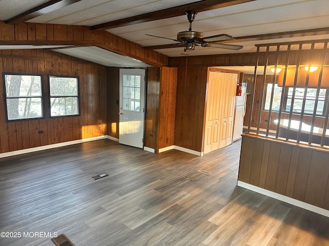 empty room with vaulted ceiling with beams, ceiling fan, dark hardwood / wood-style flooring, and wood walls