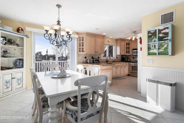 dining space featuring sink, ceiling fan with notable chandelier, and light tile patterned flooring