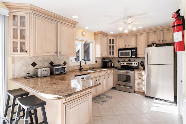 kitchen with sink, a kitchen breakfast bar, light tile patterned floors, kitchen peninsula, and stainless steel appliances