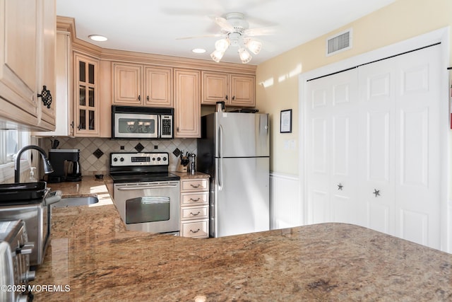 kitchen featuring sink, ceiling fan, appliances with stainless steel finishes, backsplash, and stone countertops