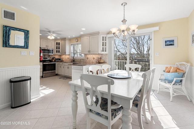 dining space with light tile patterned floors, ceiling fan with notable chandelier, a wealth of natural light, and sink