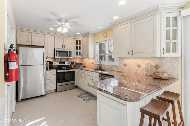 kitchen featuring light tile patterned flooring, sink, a breakfast bar area, appliances with stainless steel finishes, and kitchen peninsula