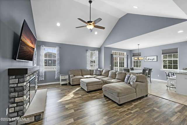 living room featuring ceiling fan with notable chandelier, a fireplace, high vaulted ceiling, and plenty of natural light