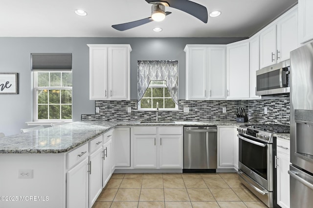 kitchen featuring stainless steel appliances, kitchen peninsula, sink, and white cabinets