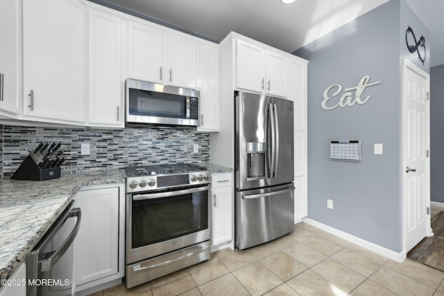 kitchen featuring light tile patterned floors, backsplash, stainless steel appliances, light stone countertops, and white cabinets