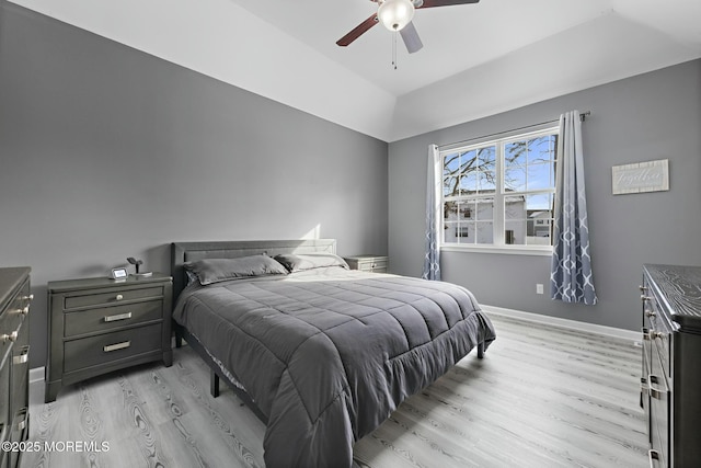 bedroom featuring ceiling fan, a tray ceiling, and light wood-type flooring