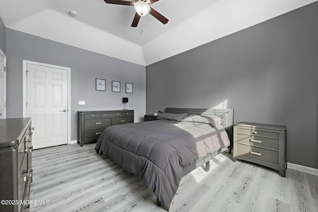 bedroom with ceiling fan, lofted ceiling, a raised ceiling, and light hardwood / wood-style flooring