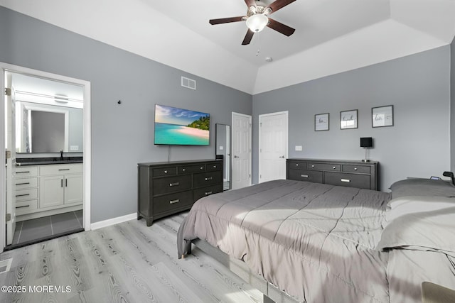 bedroom with vaulted ceiling, connected bathroom, sink, ceiling fan, and light hardwood / wood-style floors