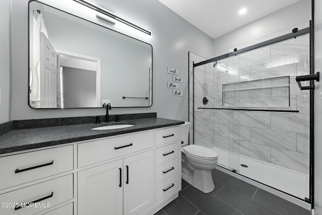 bathroom with a shower with door, vanity, tile patterned flooring, and toilet