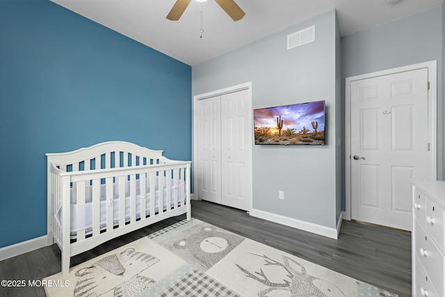 bedroom featuring a nursery area, ceiling fan, dark hardwood / wood-style floors, and a closet