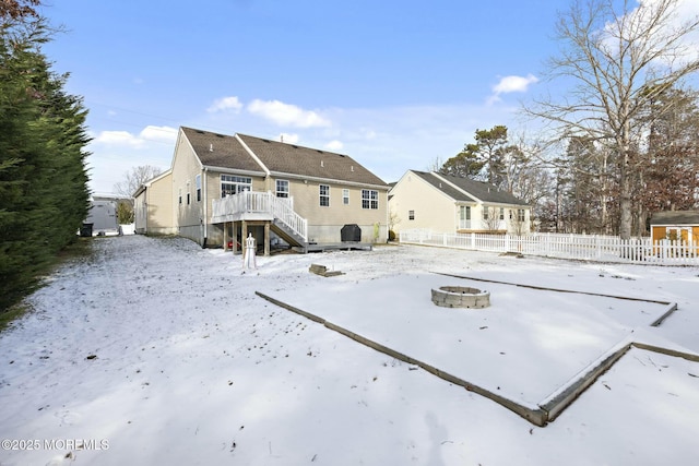 snow covered rear of property featuring a wooden deck and a fire pit